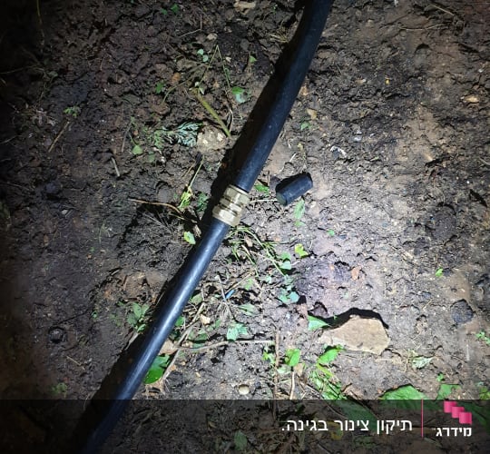 צינור שחור עם מחבר מתכת על אדמה
